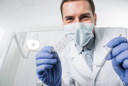 口服手持牙科仪器的手套和面罩有选择地突出牙医的乳图片