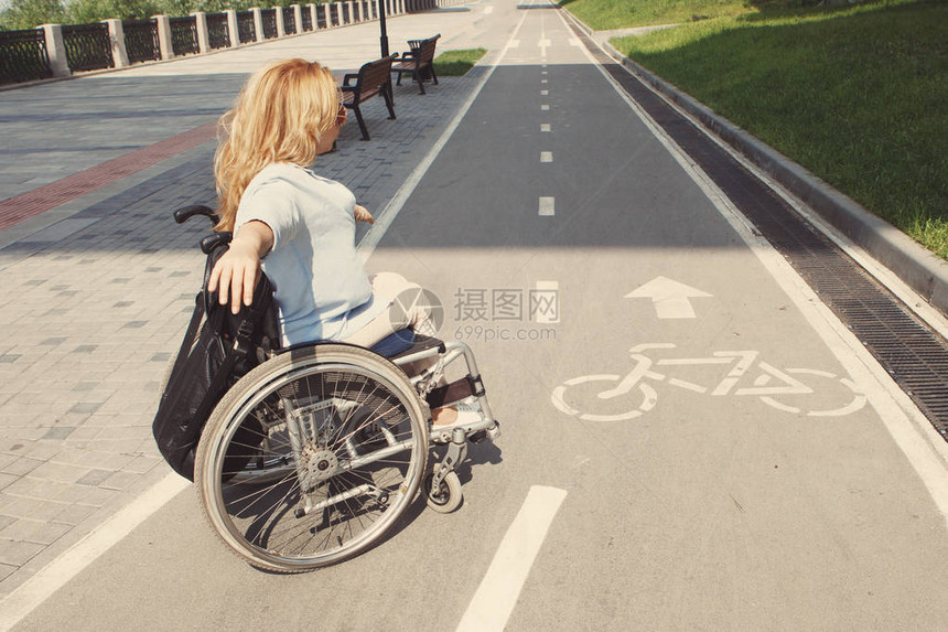妇女乘坐轮椅在城市夏季图片