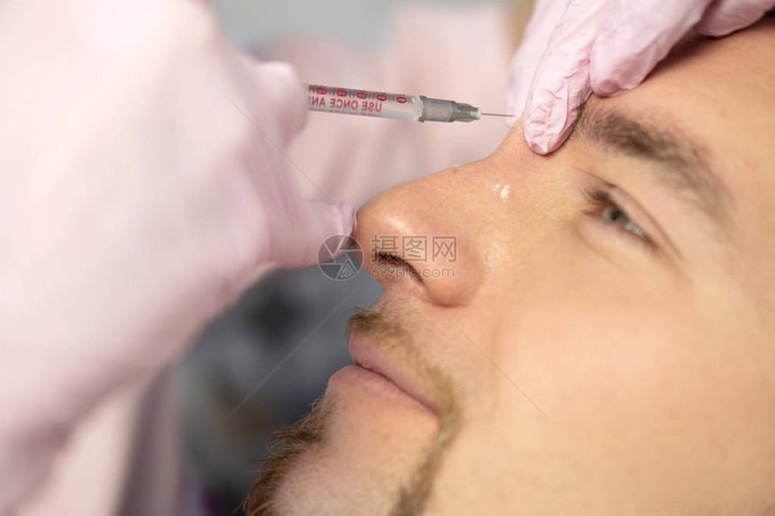 美容大师在年轻男患者脸上注射的特写镜头男子接受使用填充剂注射的美容程序面部注射的美图片