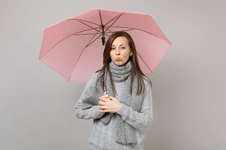 冒犯了身穿灰色毛衣围巾噘嘴拿着粉色雨伞的年轻女子图片