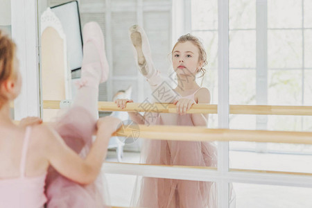舞蹈课上的年轻古典芭蕾舞演员女孩美丽优雅的芭蕾舞女演员在白光大厅的大镜子附近穿着粉色短裙背景图片