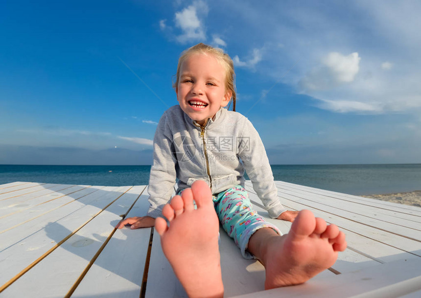 夏天海滩的小俏丽的女孩开朗的小女孩在蓝天和夏日大海的背景下笑着快乐的小女孩在沙滩上玩图片