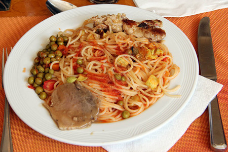 在餐厅粉条肉豌豆酱菜用叉子和刀意大利面配肉蔬菜和酱汁盘子里有牛肉和豌豆图片