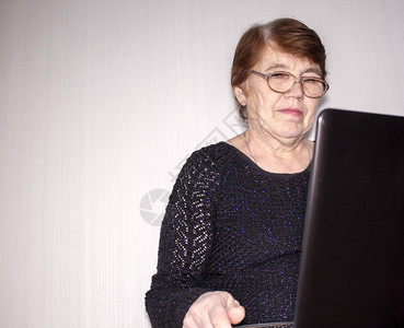 一位老妇人仔细阅读笔记本电脑上的信息图片
