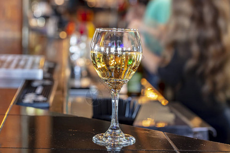 餐厅背景模糊的木质台面吧台上传统圆形高脚杯形状的水晶透明酒杯的低图片