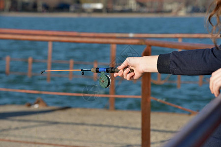 一个人的手拿着一根钓鱼竿在水面上钓鱼高清图片