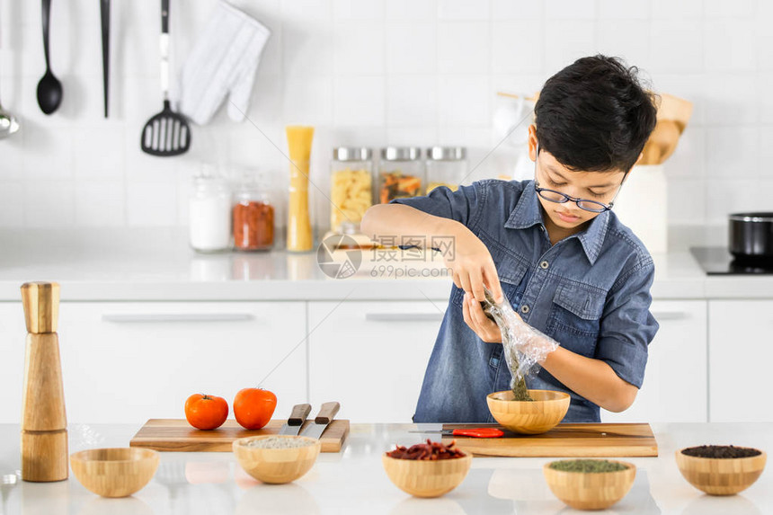 亚洲男孩故意将香料粉倒在木制容器中图片