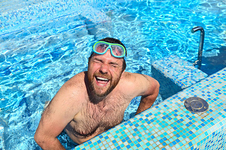 跳水面具的有趣的男人在泳池中跳图片