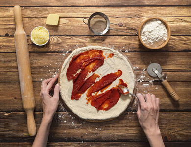 做比萨饼番茄酱在生披萨面团图片