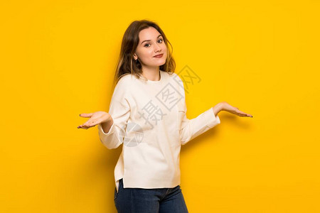 十几岁的女孩在黄墙上做一个不重要的手势图片