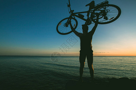 日落背景上骑自行车的人剪影正把自行车图片