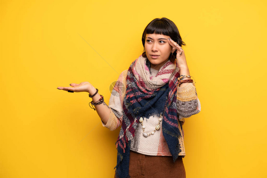 年轻嬉皮女青年在黄墙上做一个疯狂的手势图片