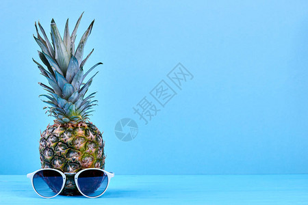 带太阳镜和复制空间的菠萝新鲜的菠萝水果和太阳镜在蓝色背景与文本空图片