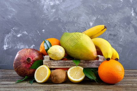 桌上的木箱里有一大堆异国水果香蕉橙子基维石榴芒果图片