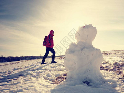 年轻人在雪地上的春天景观中走到融化的播种人徒步旅行者背着包图片