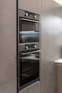 黑厨房橱柜内新的和现代内置烤炉上闭图片