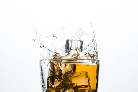 白色背景上的冰块中的威士忌飞溅含冰威士忌或白兰地苹果汁和冷却饮料的酒图片