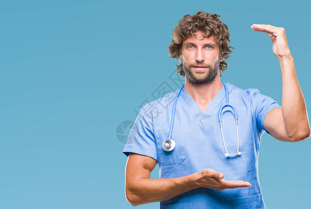 英俊的西班牙外科医生在孤立的背景下用双手展示大小的标志图片