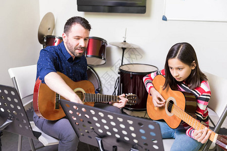音乐老师在吉他课上为学前女孩提供工具音乐教图片