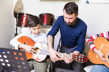 协助男孩在音乐学校习吉他弹吉他基本图片