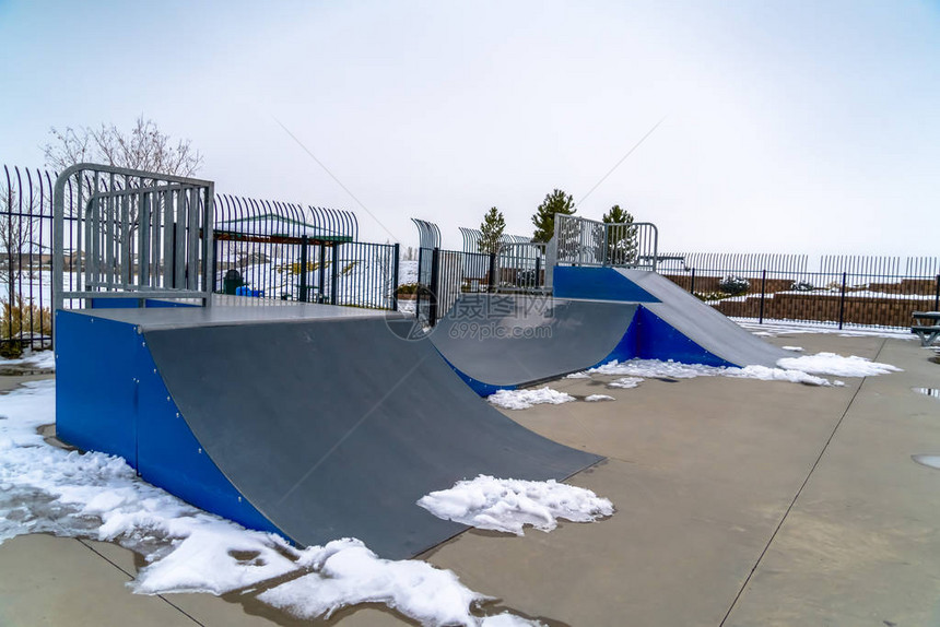 滑板坡道和滑板公园上融化的雪滑板坡道周围有融化的雪滑板公园背景是雪覆盖的地形和广阔的天图片