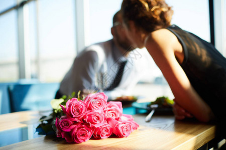阳光照耀的桌子上的粉红玫瑰团和年轻的爱美情侣图片