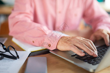 高级男子手握膝上型电脑键盘和手指在图片