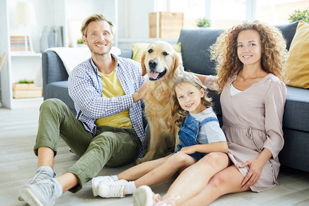年轻现代家庭微笑的成员和他们的纯种友善宠物在家图片