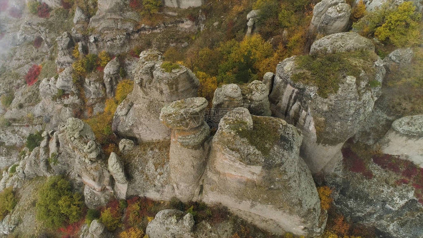 山上形状奇特的石头被雾云覆盖山中雾天的鸟瞰图和美丽的石头与黄色秋天图片