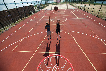 两个篮球运动员在户外法庭上跳球的宽角动作镜头图片