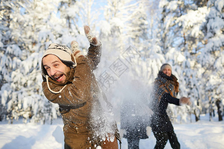 快乐家庭在美丽的冬季森林中享受雪球打斗的肖像关注露着胡子的人在前图片