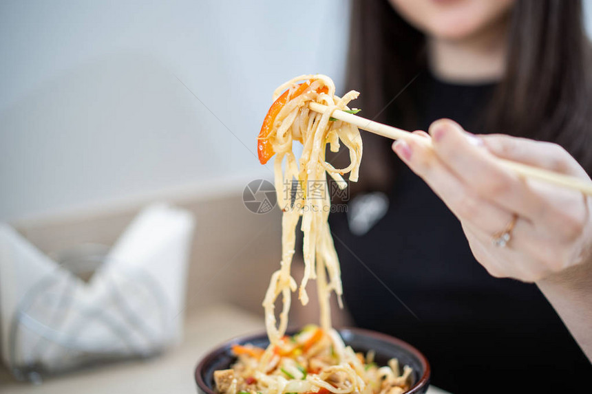 近距离的人类手拿面条从碗里用筷子和图片