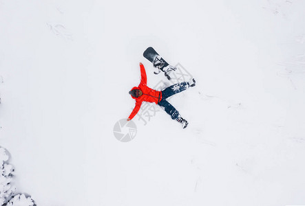 一个躺在雪中的男人的空中观视手伸向滑雪板图片