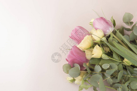 粉红色背景上美丽的郁金香花和小黄玫瑰花束图片