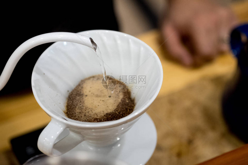 男人把水壶里的水倒进咖啡过滤器新鲜的早晨倒在滴头图片