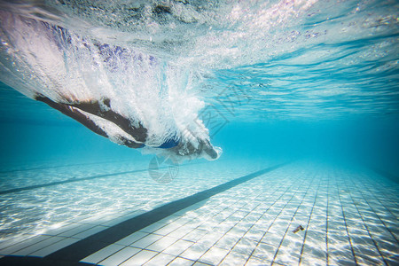 男游泳者潜水和在游泳池图片