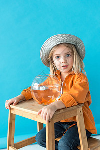 身戴银帽子和橙色衬衫的小孩坐在楼梯上图片