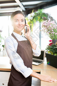 当代花店的年轻员工在用智能电话咨询客户时图片