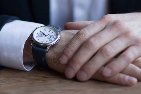 男人的手在西装与白色袖口和手臂上的手表说明有关业务时间和业图片