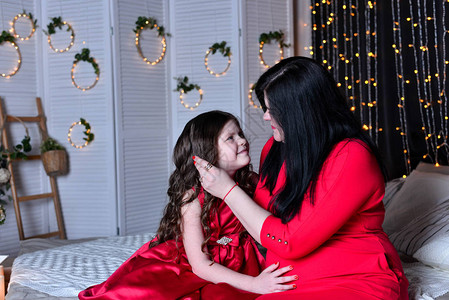 美丽的女孩和穿着红裙子的母亲在家图片