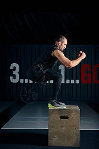 适合年轻人跳上盒子作为日常锻炼的一部分男人在健身房里做跳箱运动员图片