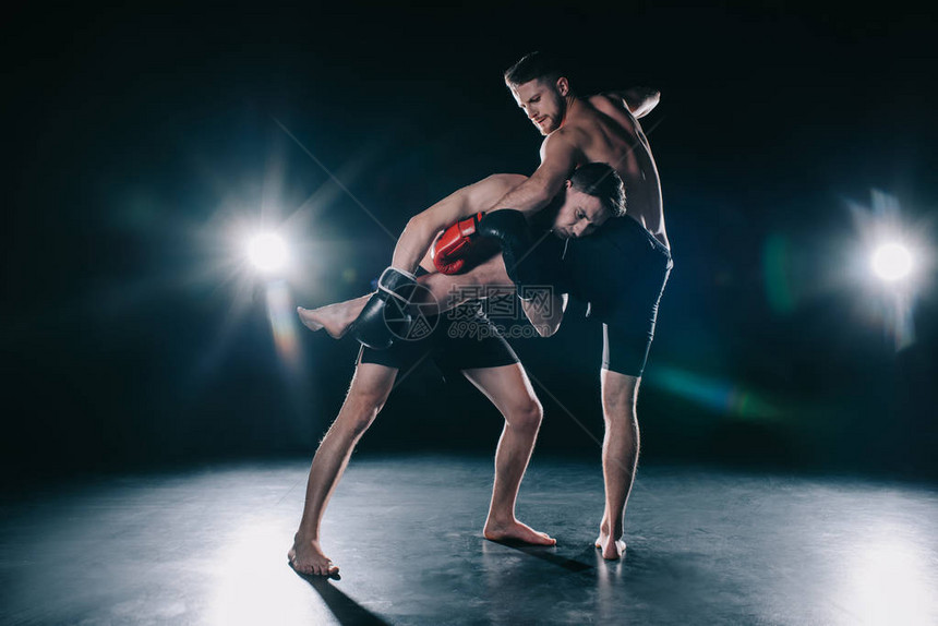 一名拳击手用拳击手套在运动员踢打他时向另图片