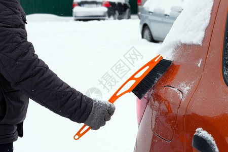 暴风雪过后有人在车上刷和铲雪背景图片