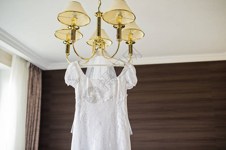 优雅的婚纱挂在酒店内部的吊灯上图片