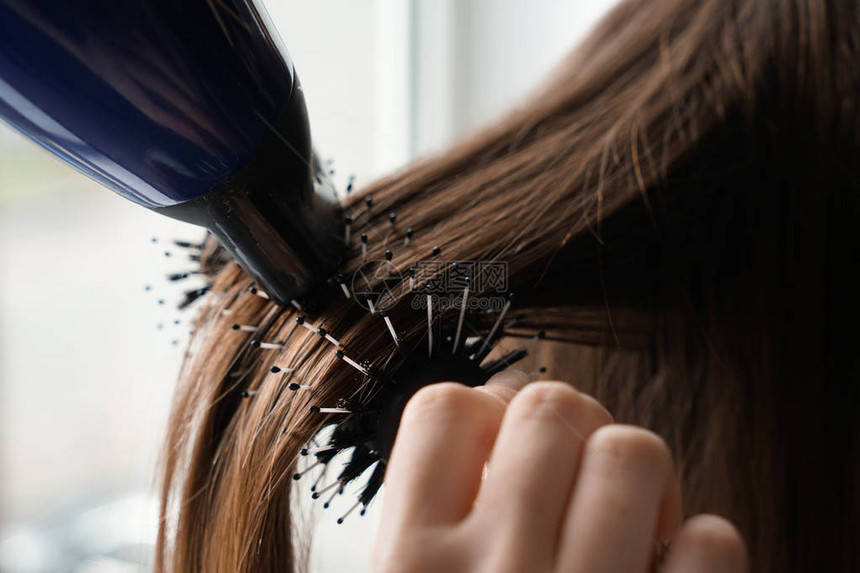 发光机吹起干燥剂在美发店为年轻女子梳图片
