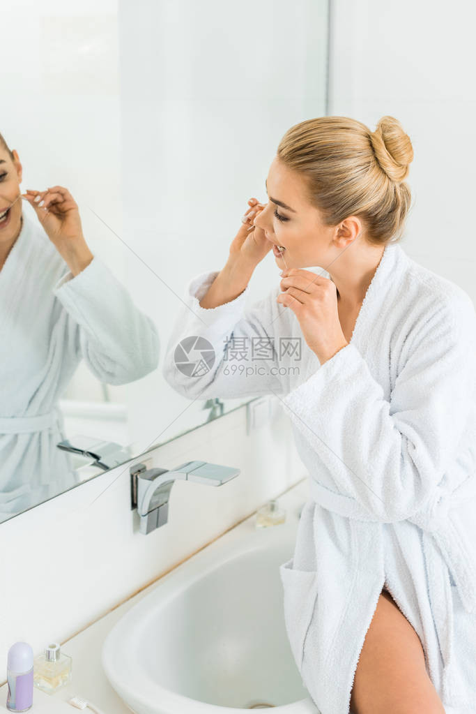 白浴袍用牙套刷牙的有吸引力和金发女子选择地聚焦于有魅图片