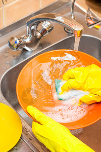 厨房顶视镜上用黄色手套的泡沫冲洗橙图片