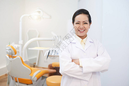 身着医疗礼服的成年笑脸亚裔妇女举手交叉图片