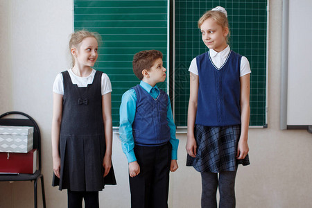 在黑板背景课堂上穿校服的小学中小学生图片