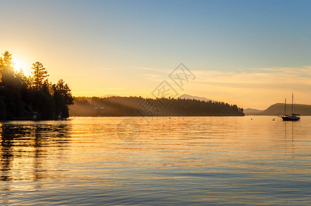 金色夏季日落在一条海湾和一艘安吉德帆船上图片